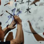 Lektor ze szkoły Mandarynka pisze pędzlem znaki chińskie