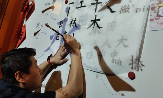 Lektor ze szkoły Mandarynka pisze pędzlem znaki chińskie